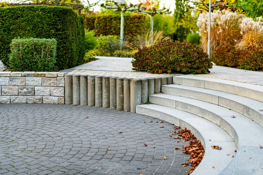 Curved stone steps and paved courtyard with clipped hedges