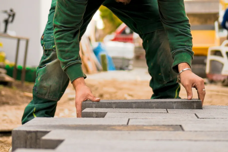Landscaper laying large-format pavers on a prepared base