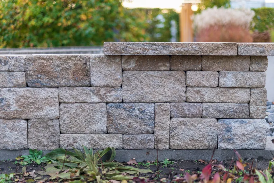 Split-face stone block wall with capping above a planted garden bed