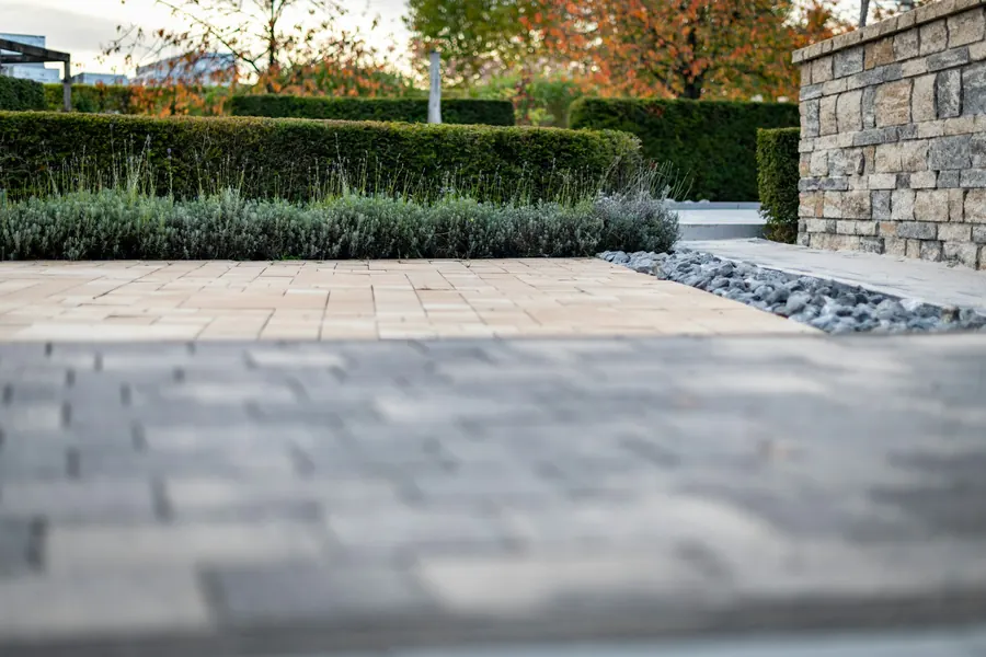 Stone block wall beside a paved garden path and hedges